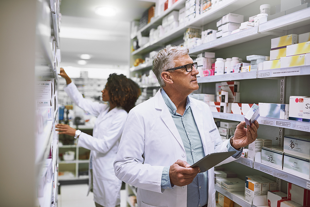 A pharmacist looking through medications on shelves at a pharmacy