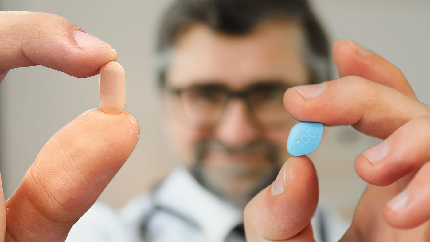 doctor holding a pink pill in one hand and a blue pill in the other