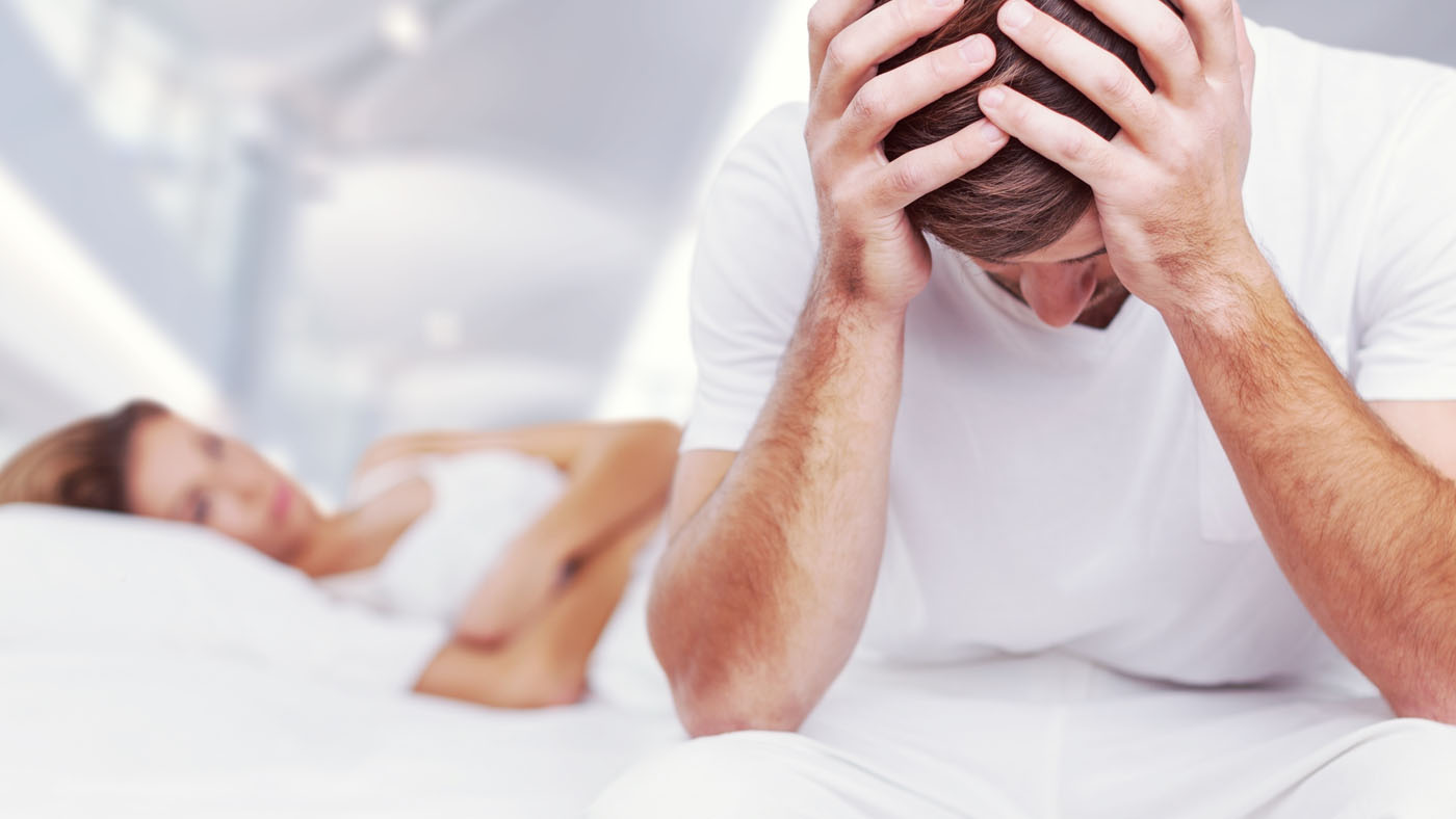 man-with-his-head-down-on-edge-of-bed-with-girl-next-to-him